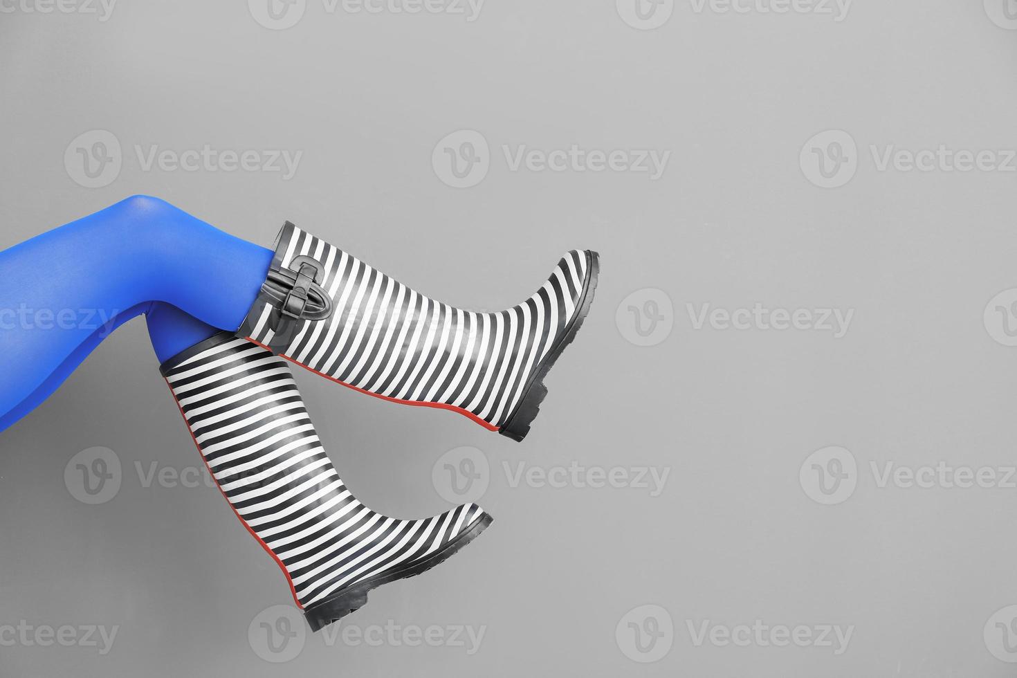 Legs of beautiful woman in stylish gumboots on color background photo