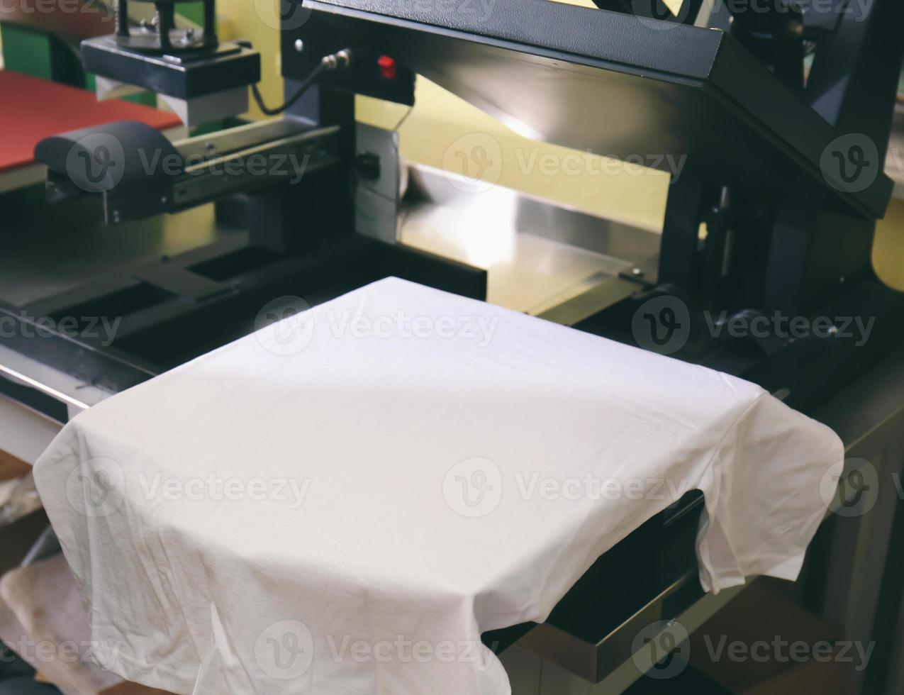 Máquina de impresión moderna con camiseta en el lugar de trabajo foto