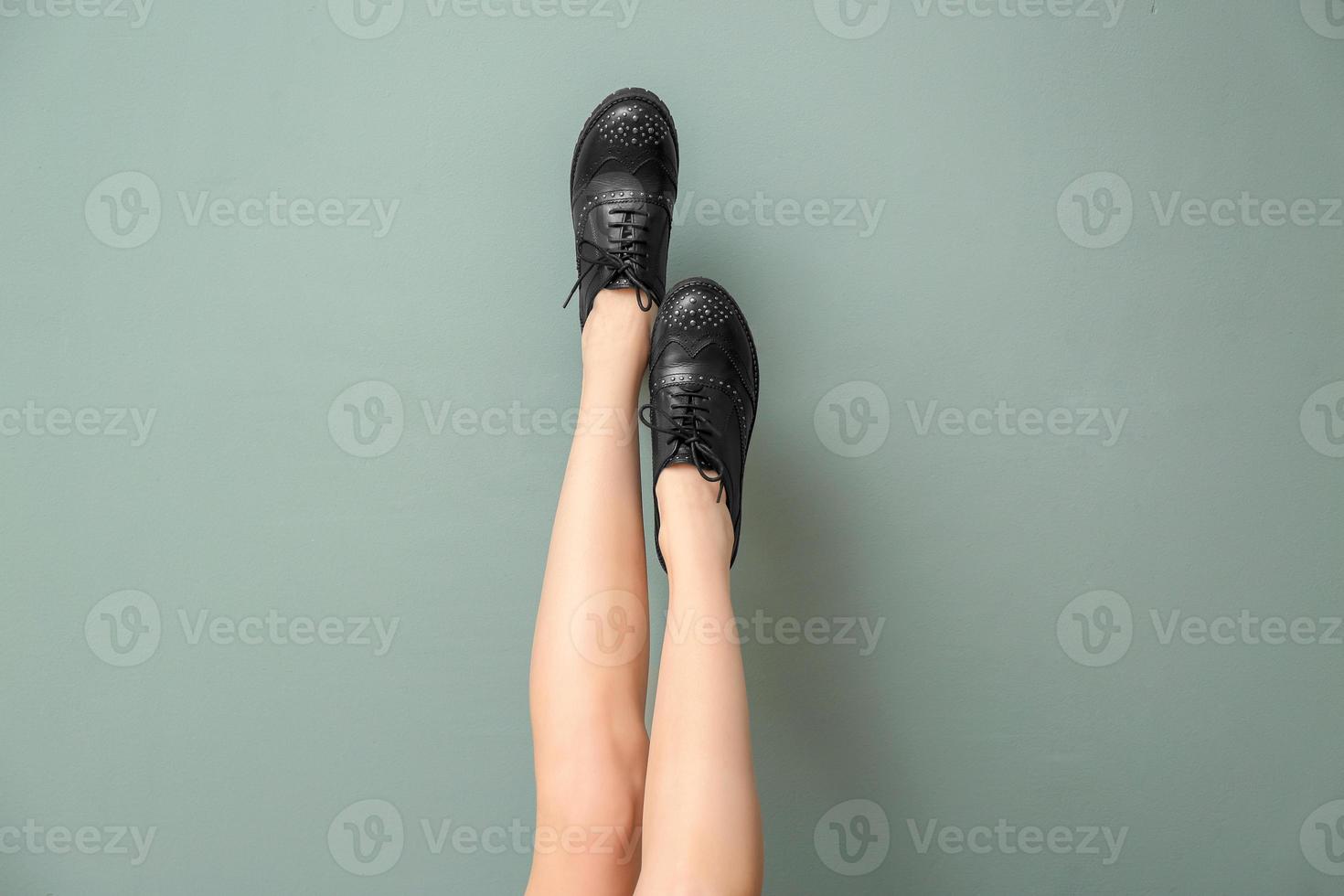 Piernas de mujer joven en elegantes zapatos casuales sobre fondo de color foto