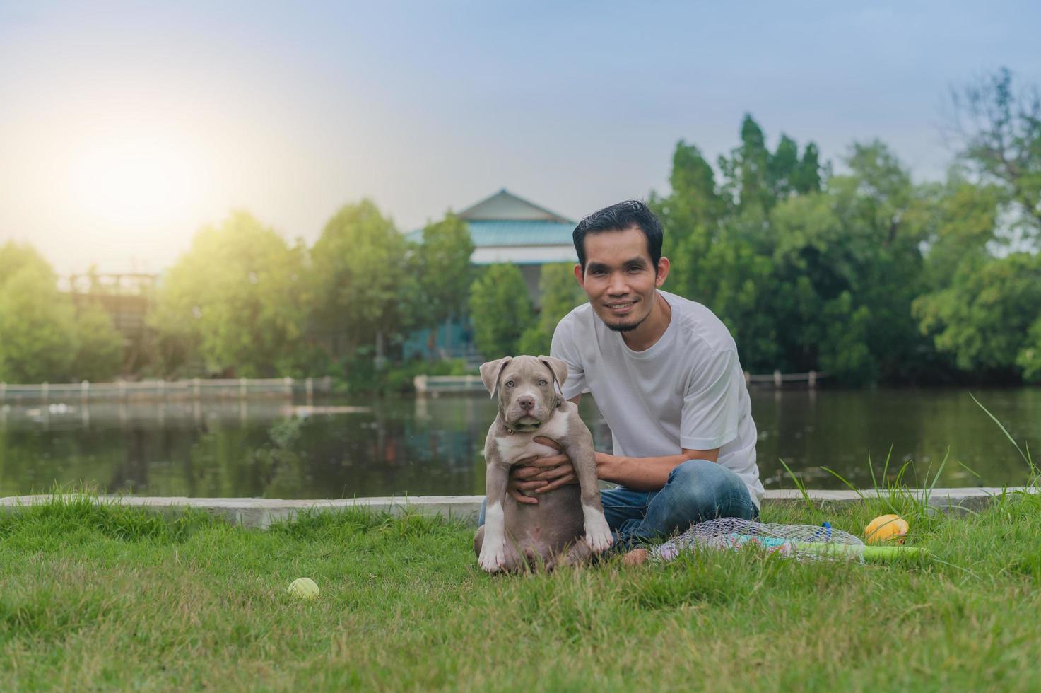 El hombre amante de las mascotas y el perro matón americano están jugando foto