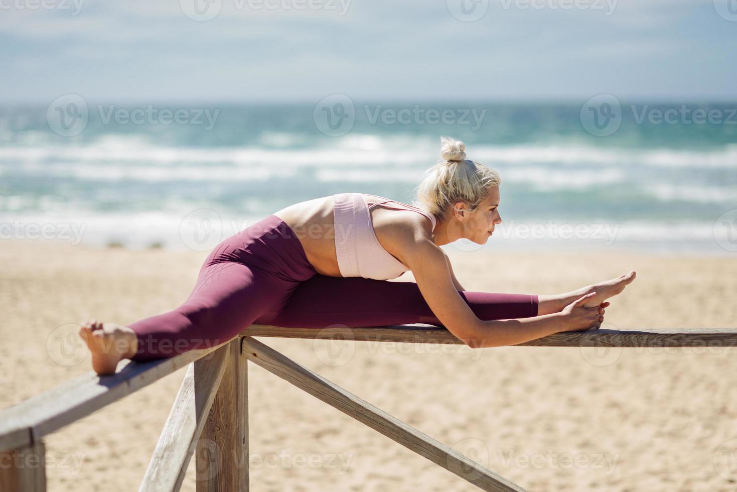 Caucasian blonde woman practicing yoga in the beach photo