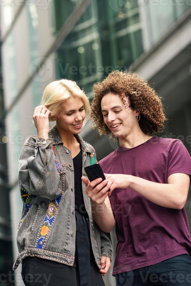 pareja feliz con smartphone en fondo urbano. foto