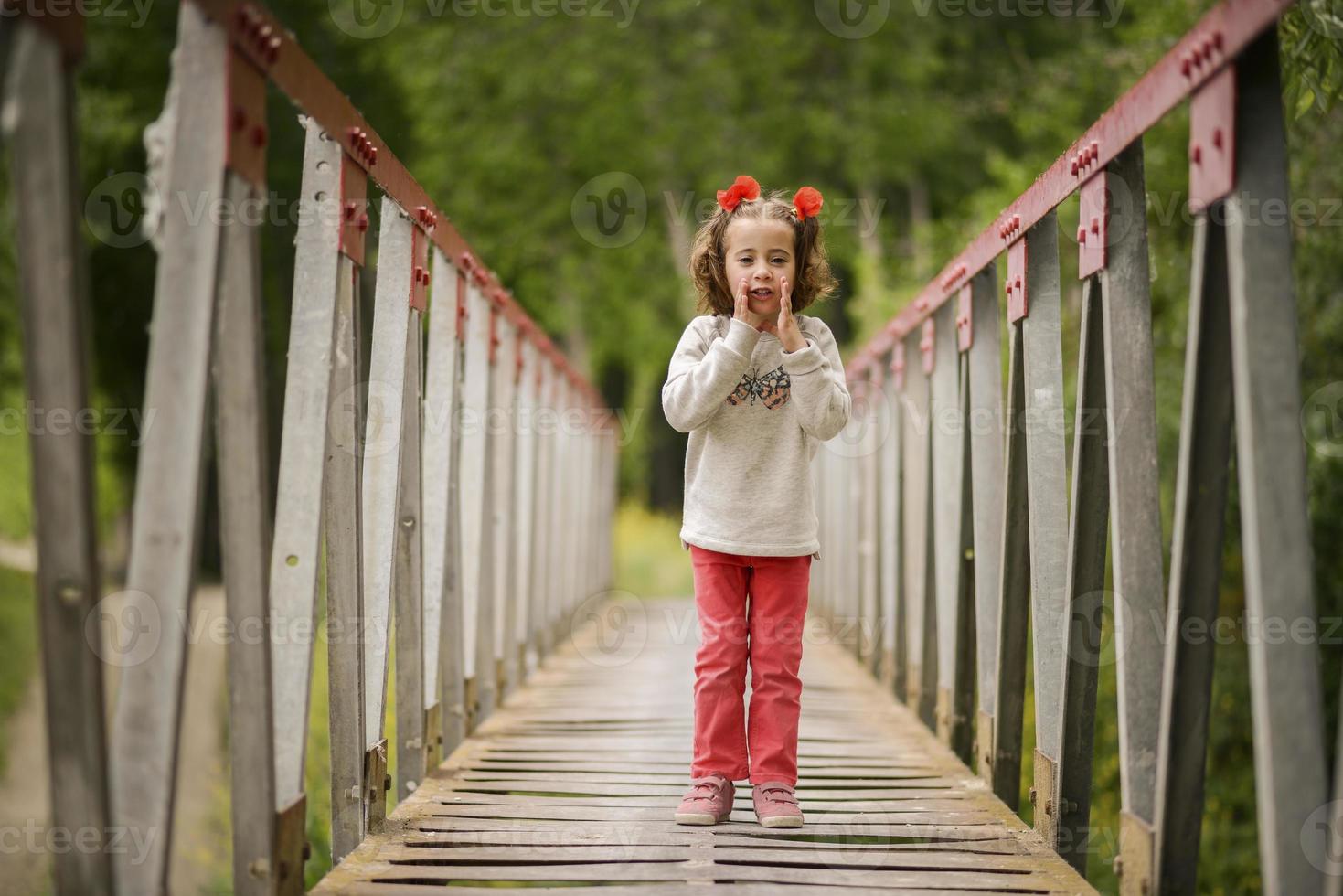 linda niña divirtiéndose en un puente rural foto