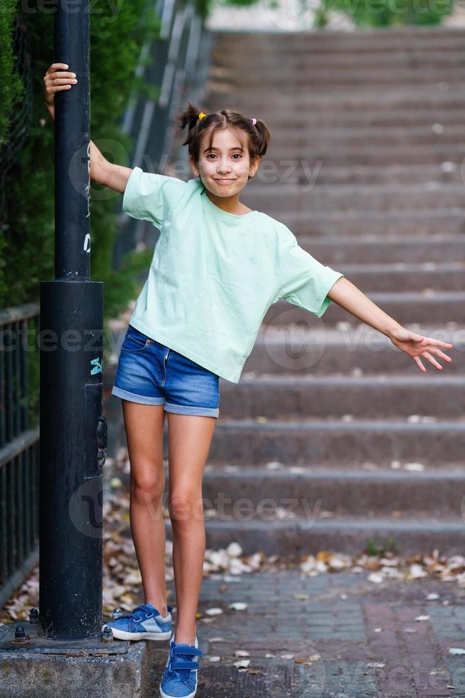 Niña de nueve años de pie en los escalones al aire libre foto