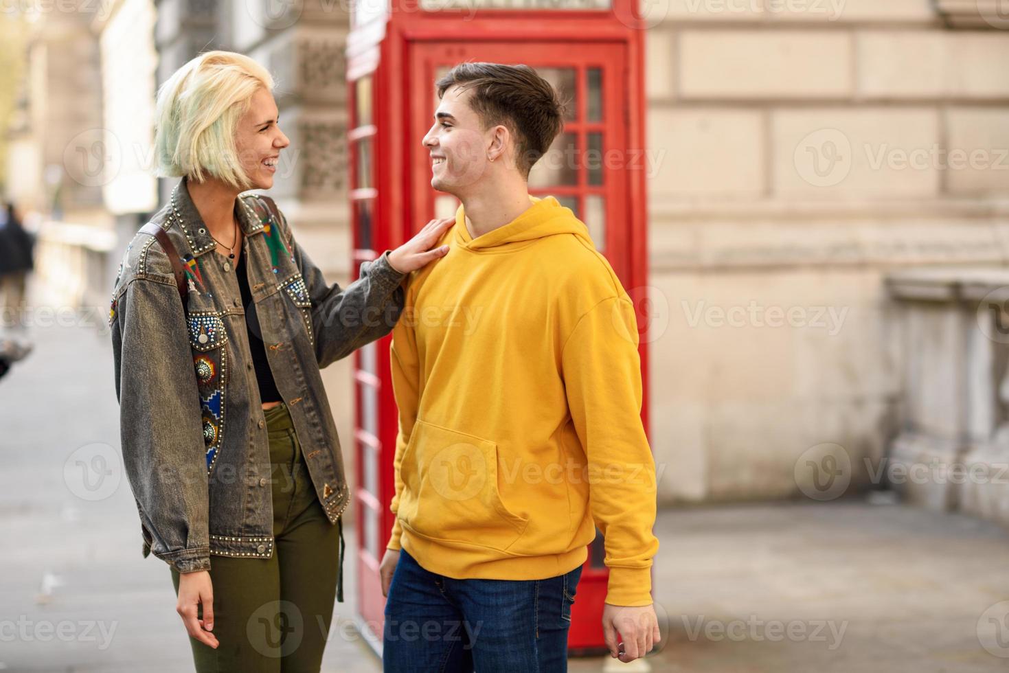 joven pareja de amigos cerca de una cabina de teléfono roja británica clásica foto