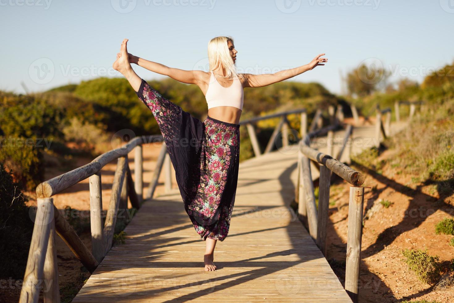 mujer caucásica practicando yoga en el puente de madera. foto