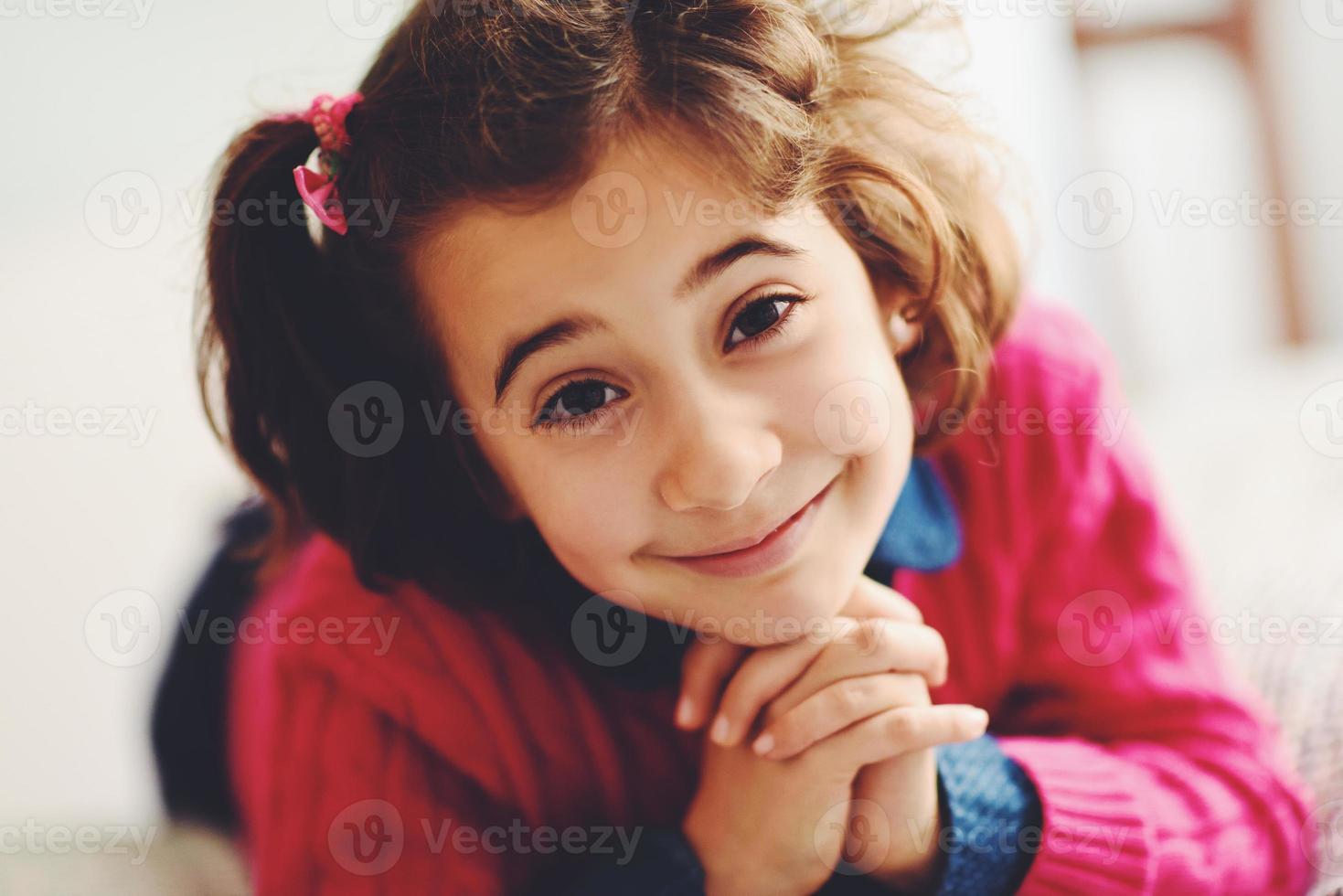 adorable niña con dulce sonrisa acostada en la cama. foto