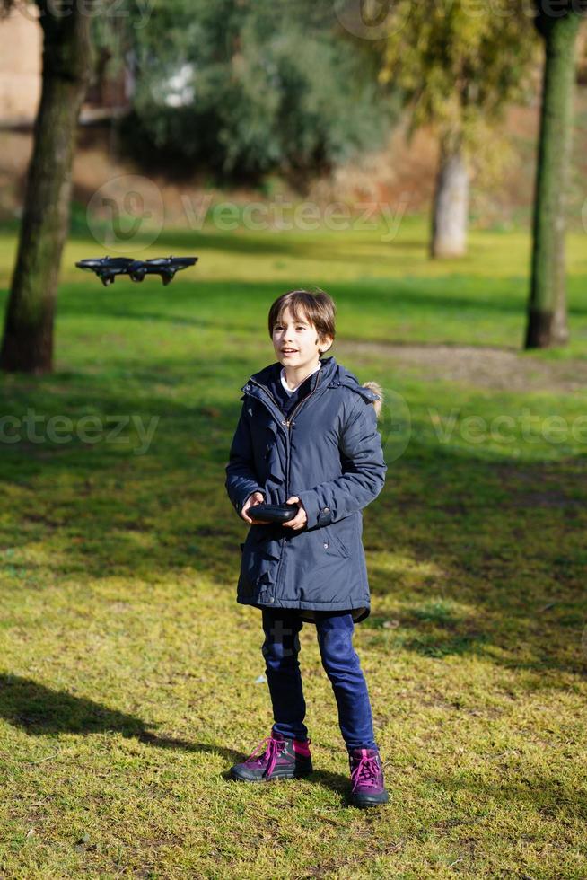 Niña de nueve años que opera un avión no tripulado de juguete volando por control remoto foto