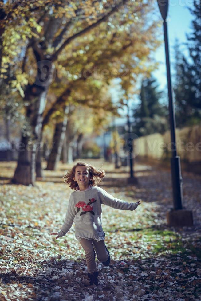 Little girl playing in a city park in autumn photo