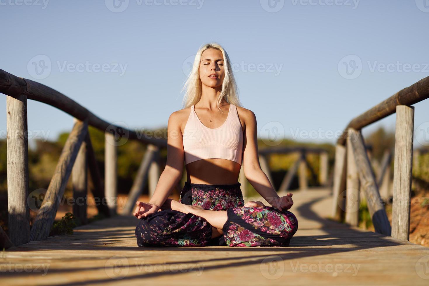 mujer caucásica practicando yoga en el puente de madera. foto