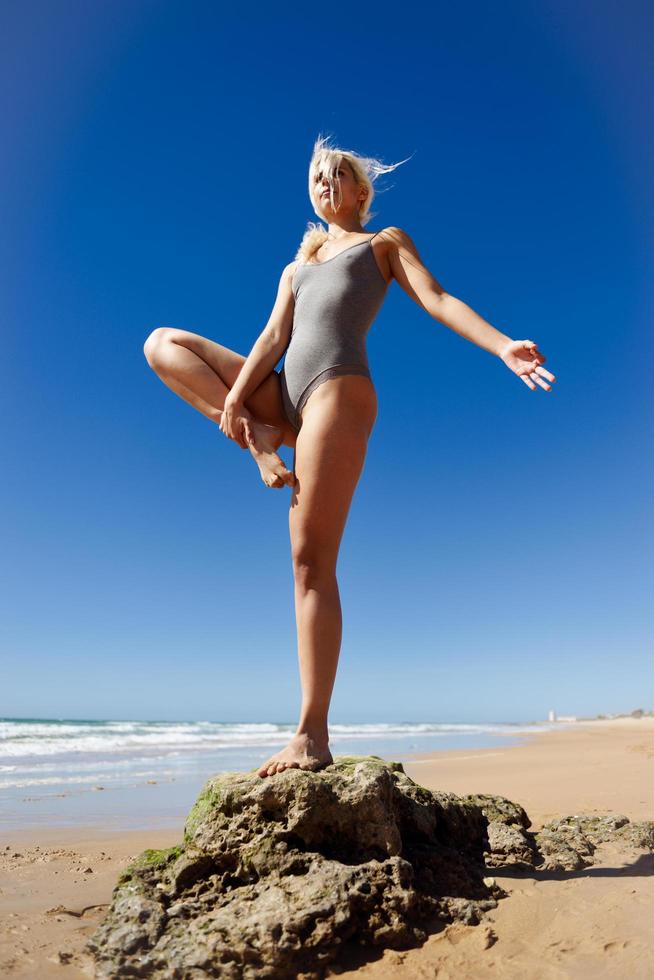 Caucasian blonde woman practicing yoga in the beach photo