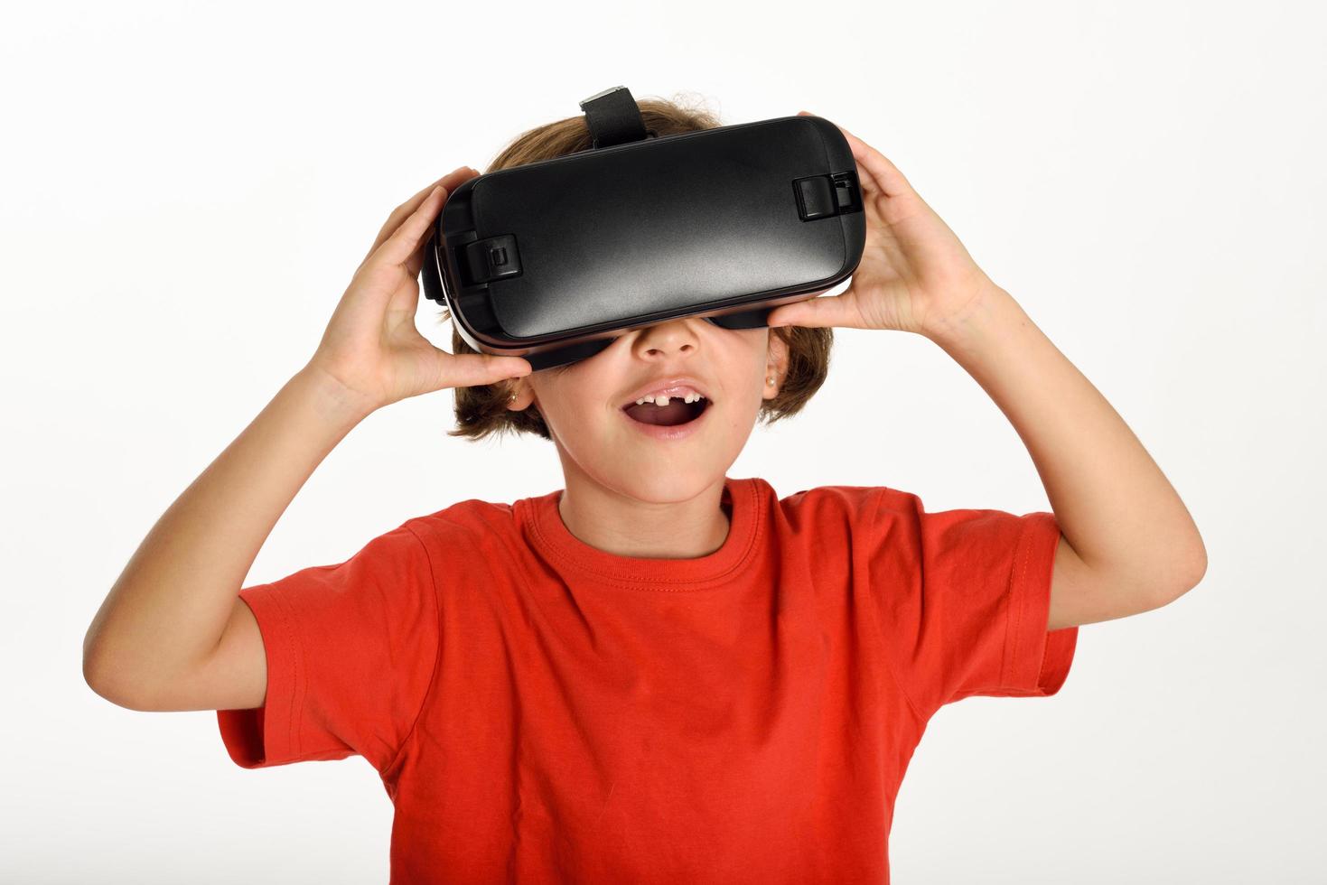 Little girl looking in VR glasses and gesturing with his hands. photo