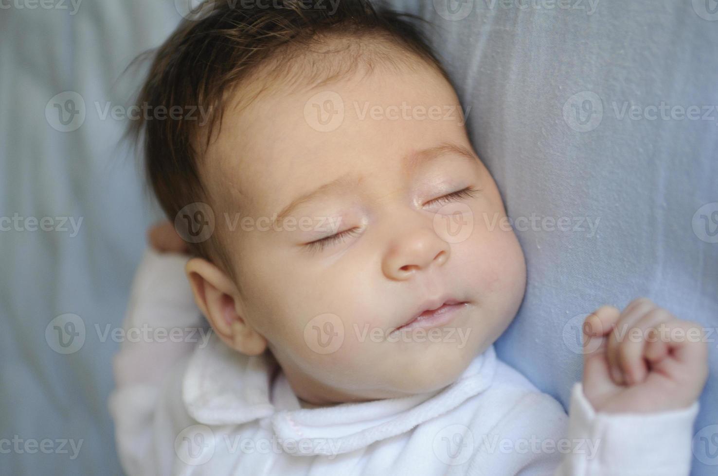 Newborn baby girl sleeping on blue sheets photo