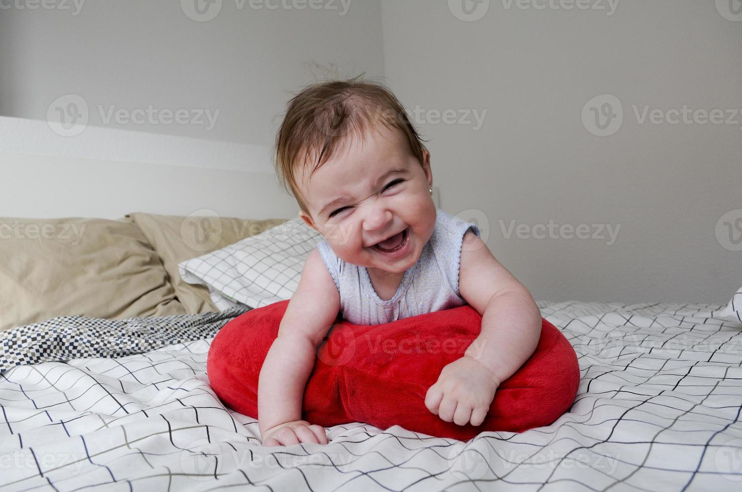 Niña acostada en la cama de sus padres con expresión divertida foto