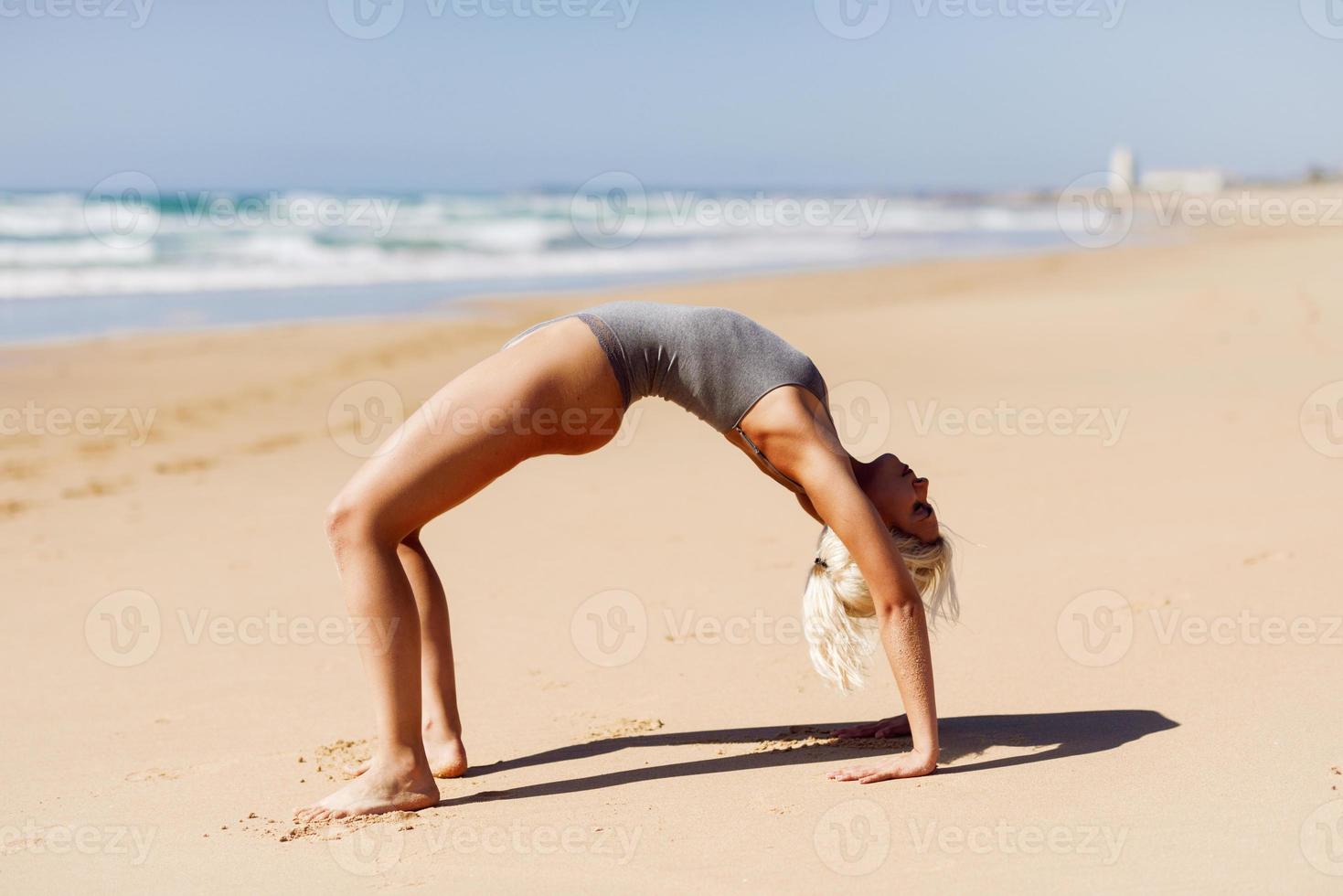 Caucasian blonde woman practicing yoga in the beach photo