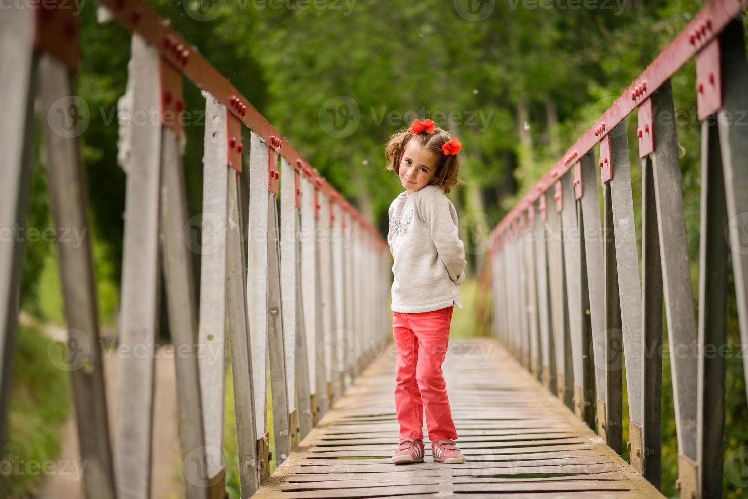 linda niña divirtiéndose en un puente rural foto