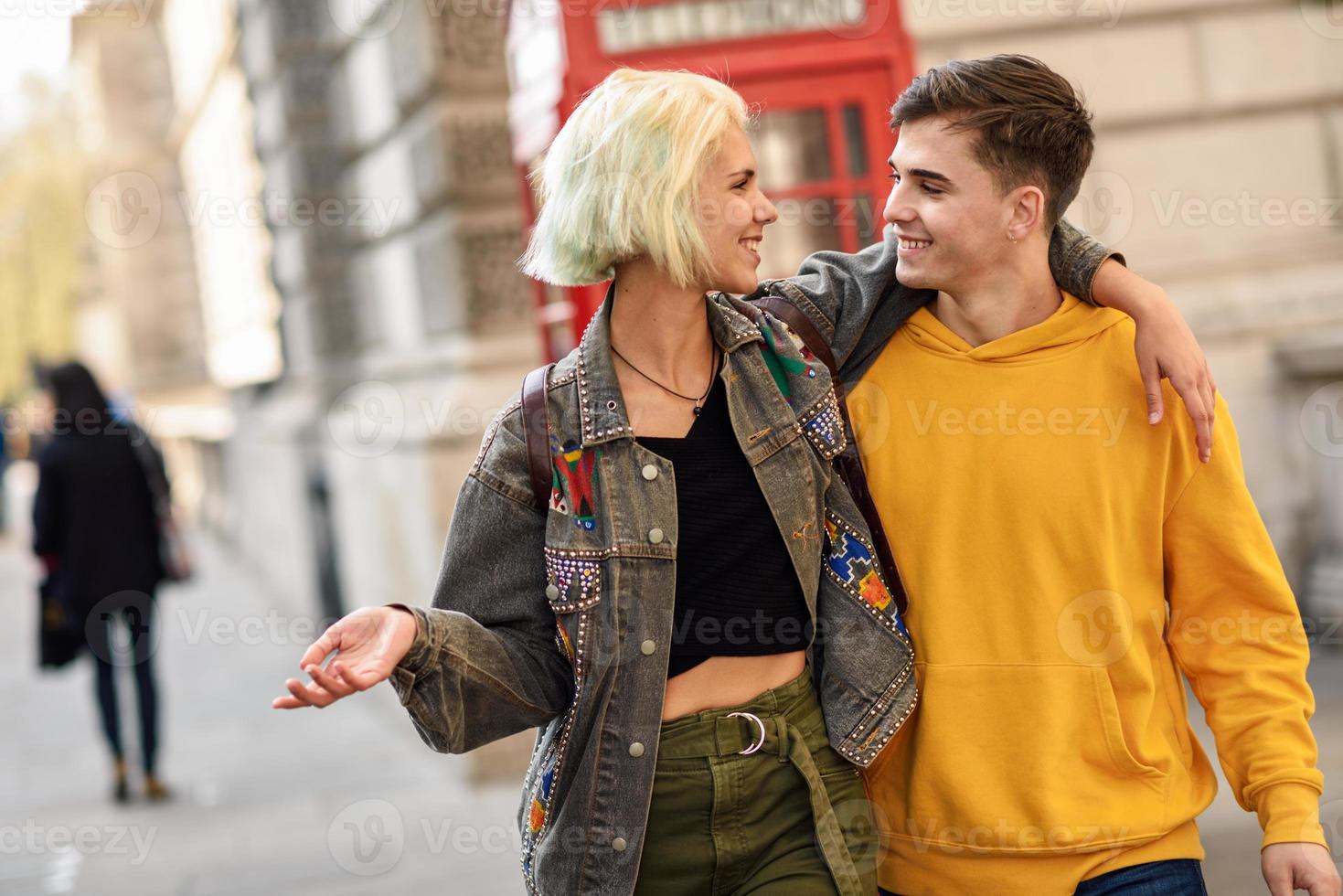 joven pareja de amigos cerca de una cabina de teléfono roja británica clásica foto