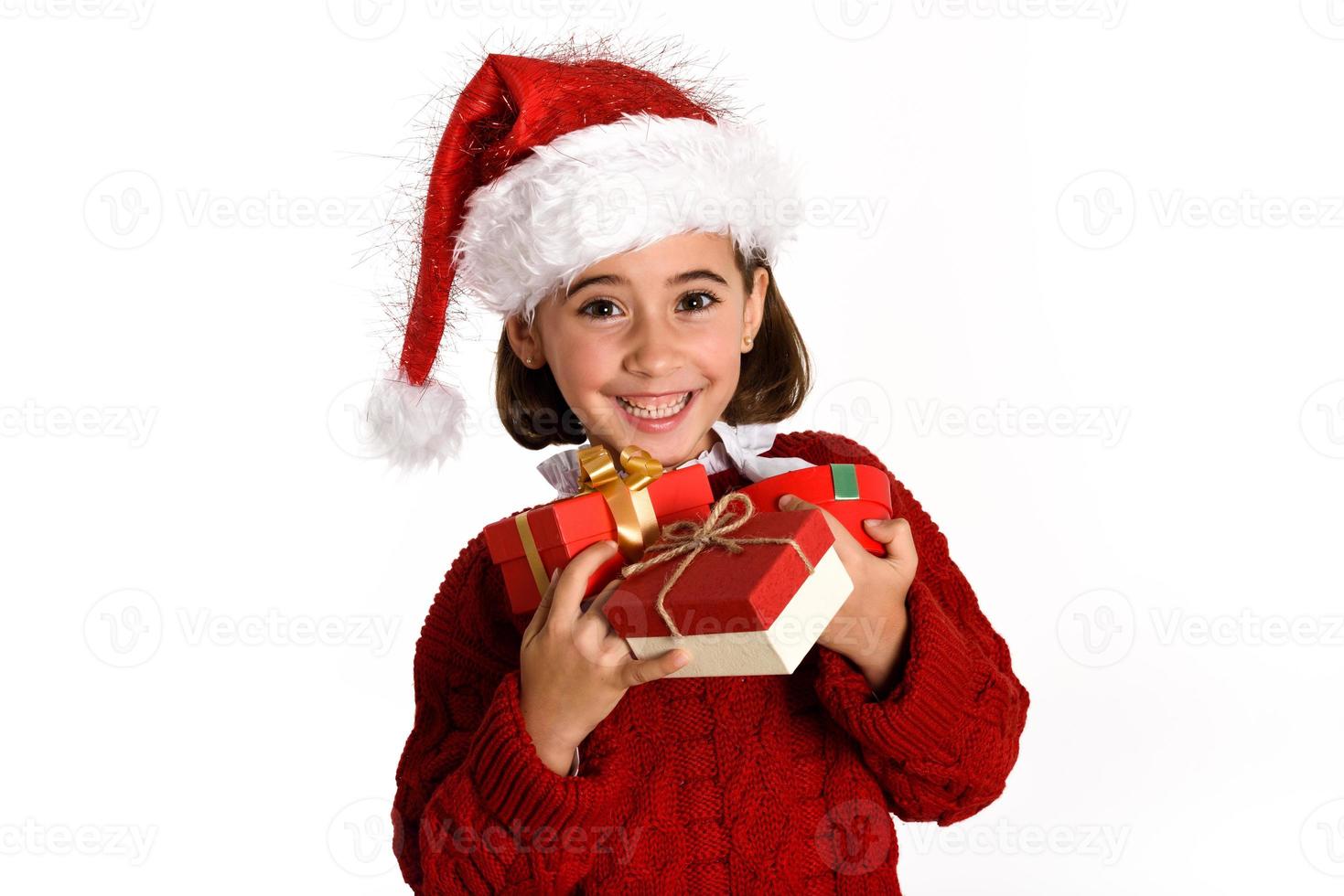 Little girl wearing santa hat carrying many gift boxes photo