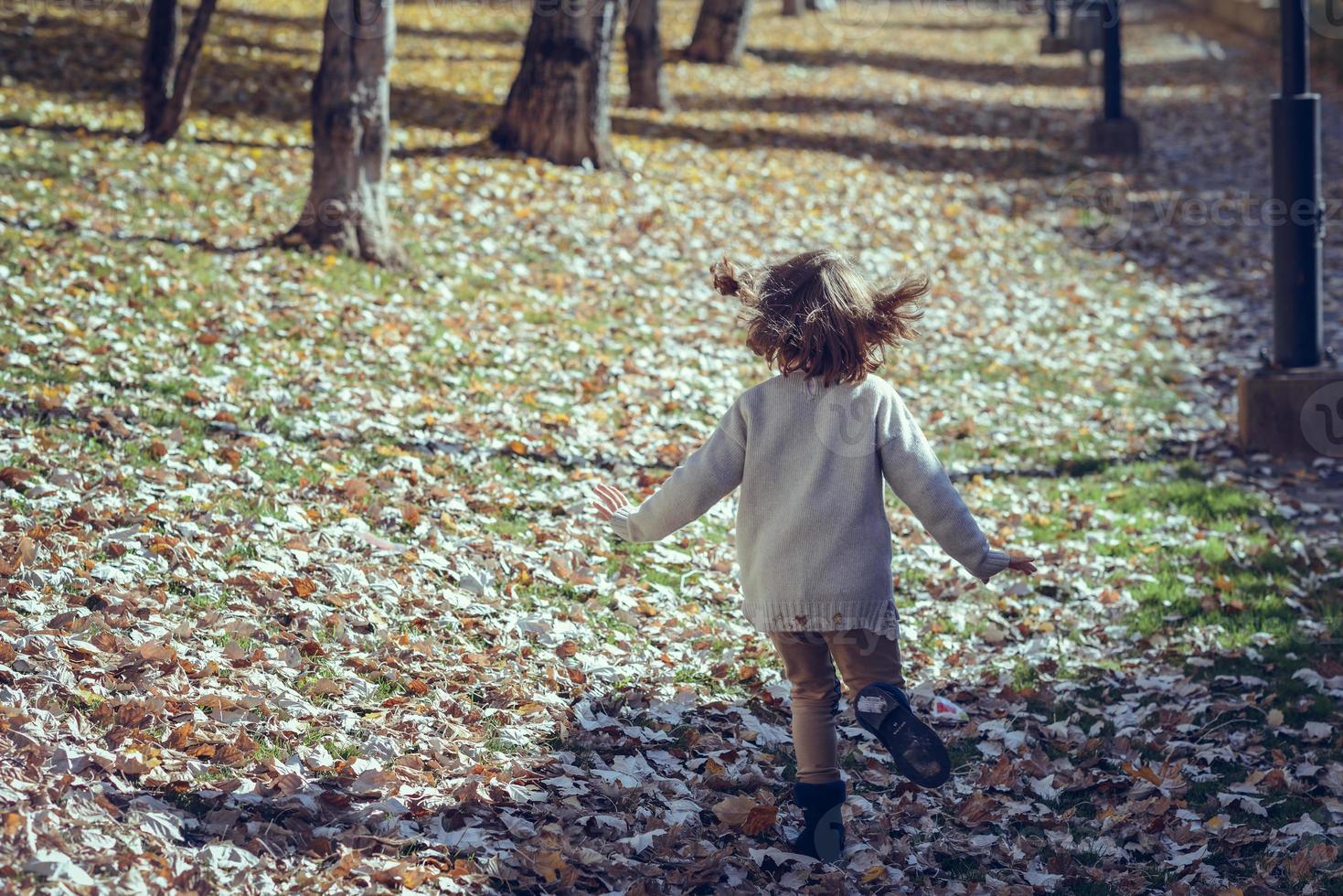 niña jugando en un parque de la ciudad en otoño foto