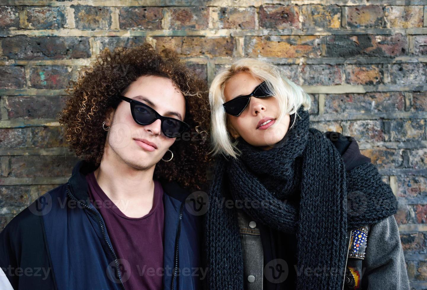 Young couple enjoying Camden town in front of a brick wall typical of London photo