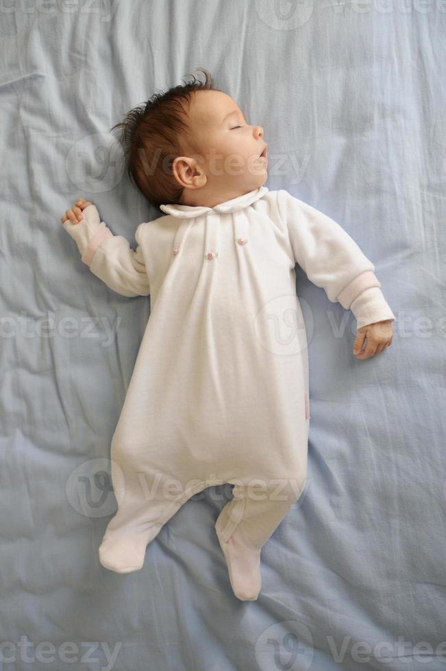 Newborn baby girl sleeping on blue sheets photo