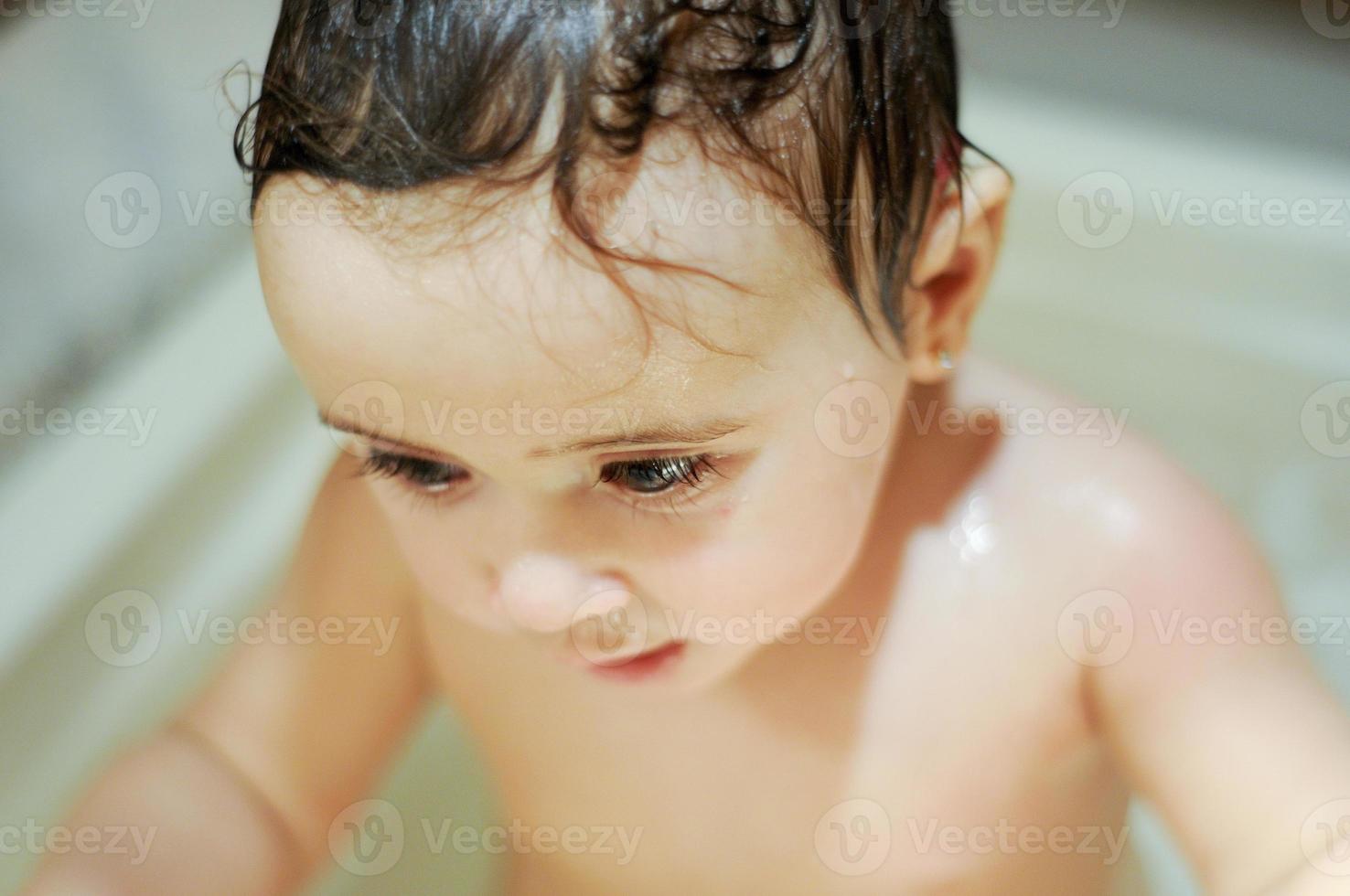 Baby girl six months old having her bath photo