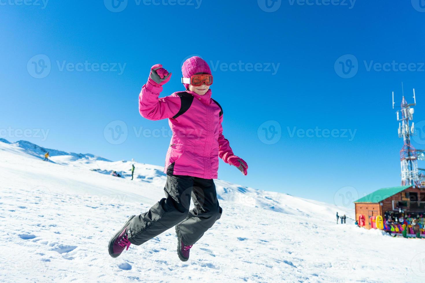 niña saltando sobre la nieve en la estación de esquí de sierra nevada. foto