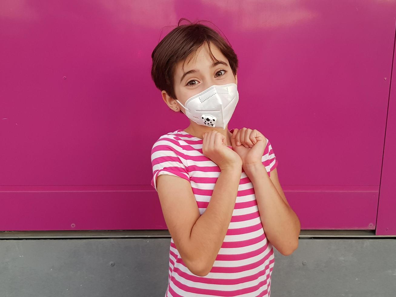 Child girl wearing a protection mask against coronavirus during Covid-19 pandemic photo