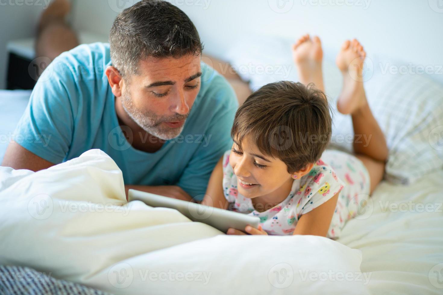 Middle-age father with her eight years daughter using digital tablet in bedroom. photo