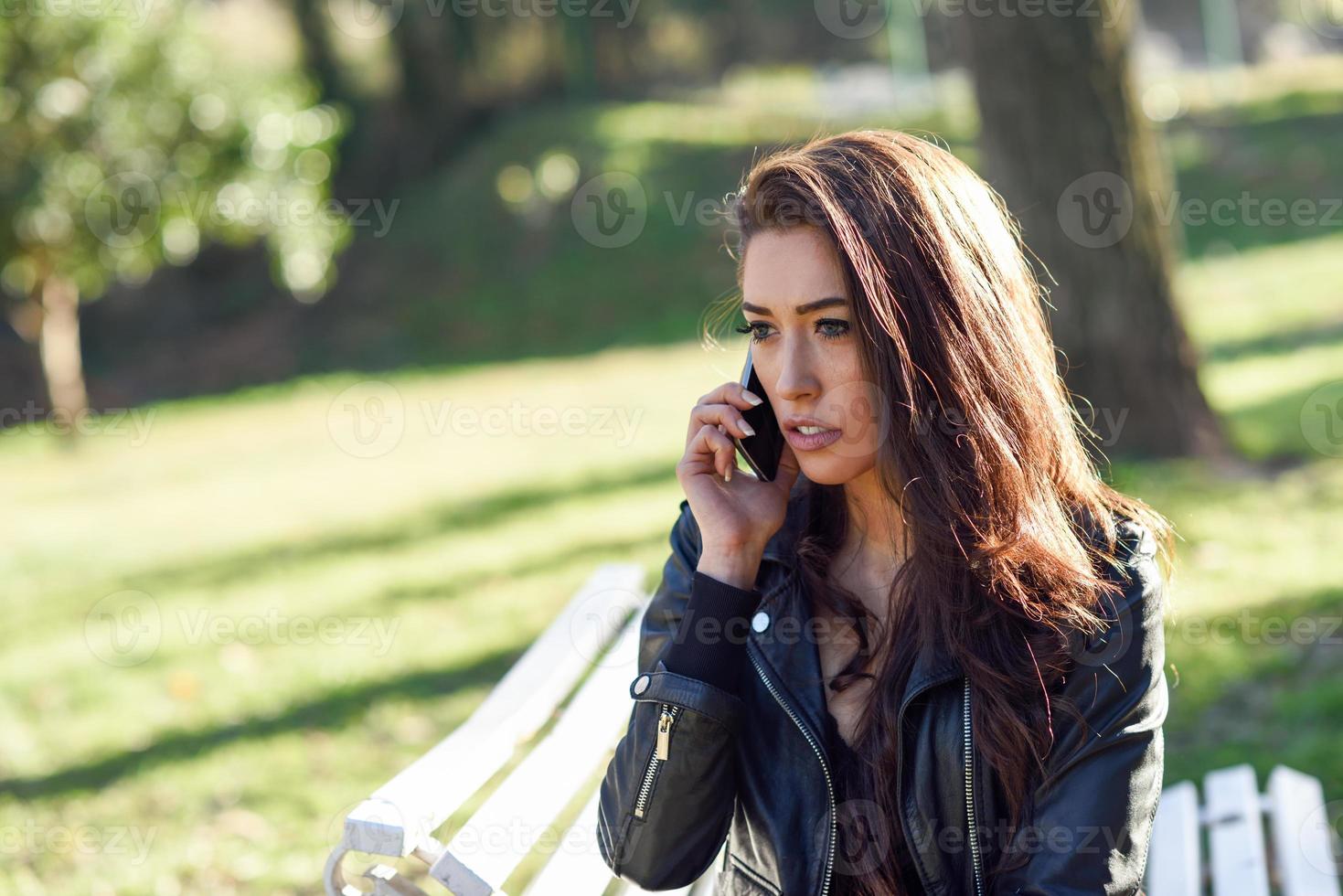 Young woman using a smartphone in an urban park photo