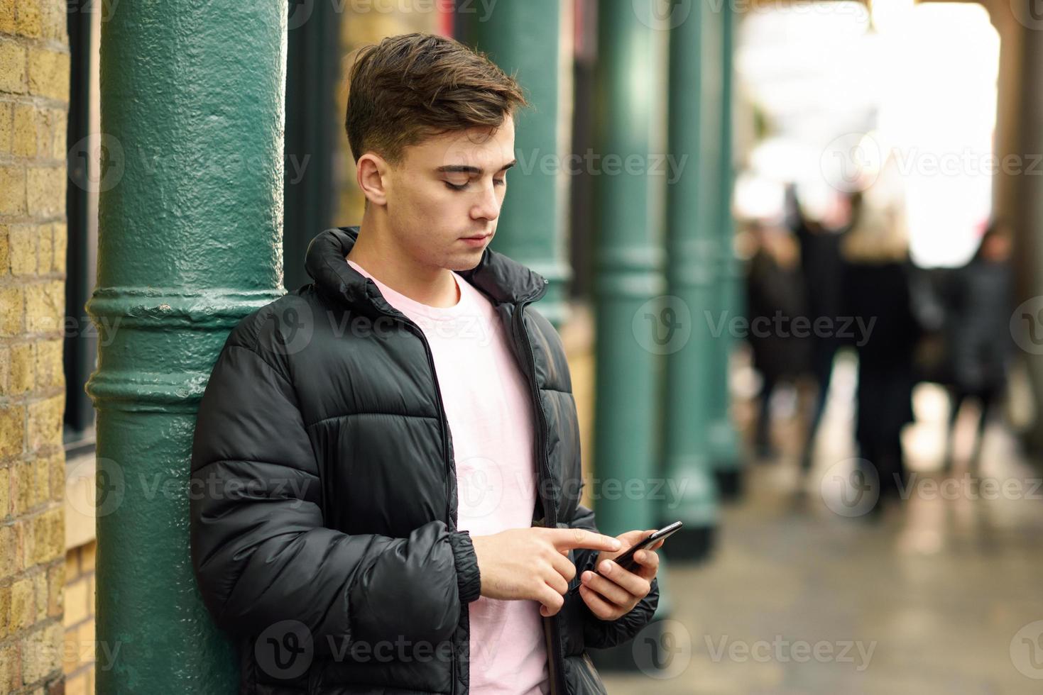joven urbano con smartphone en fondo urbano. foto