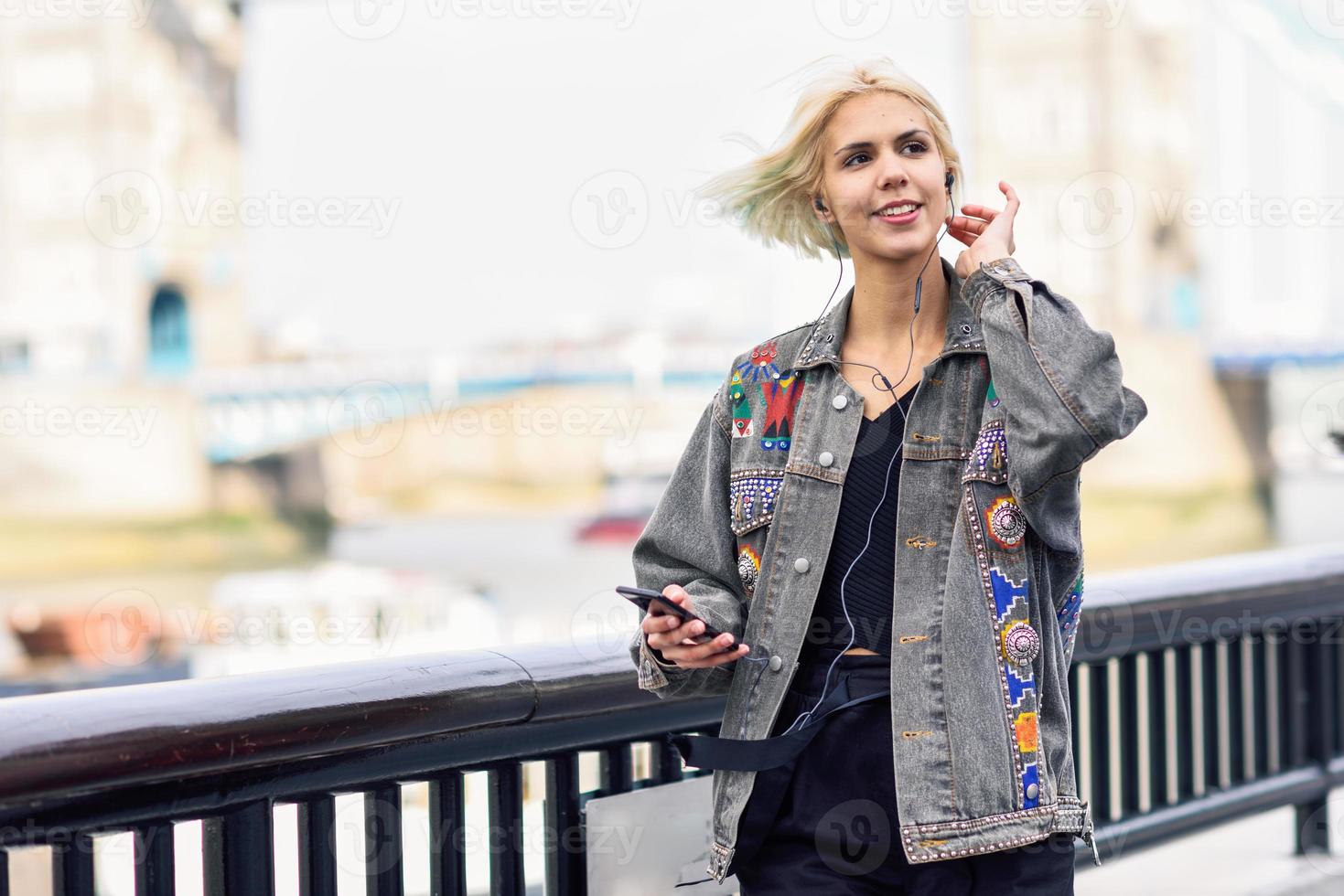 mujer joven escuchando música en el fondo urbano. foto