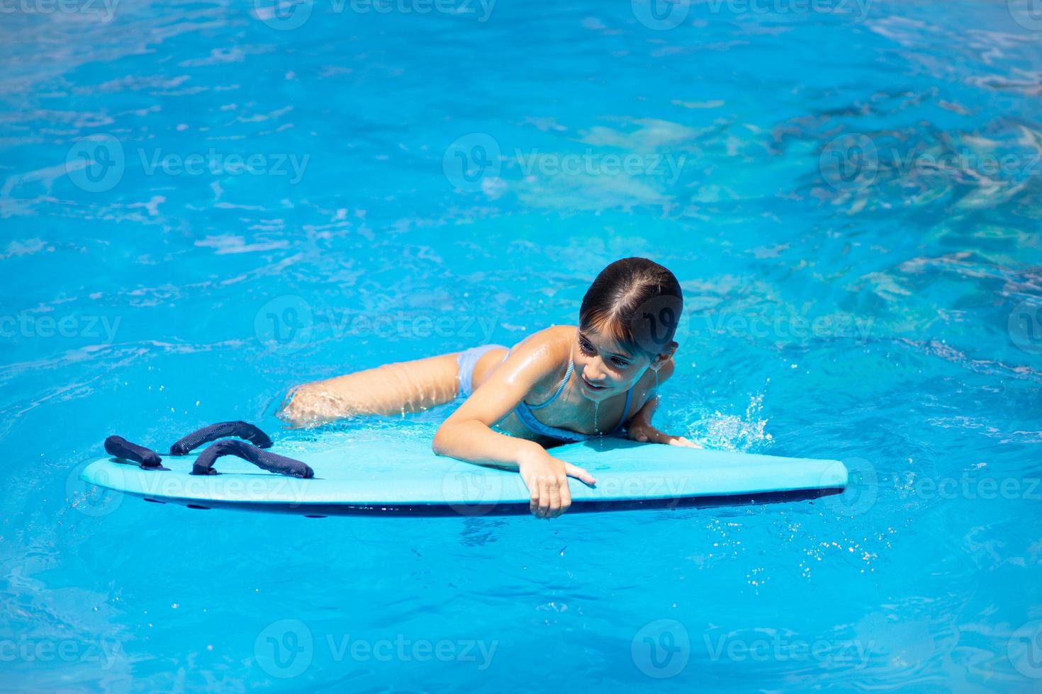 linda chica jugando con un bodyboard en una piscina. foto