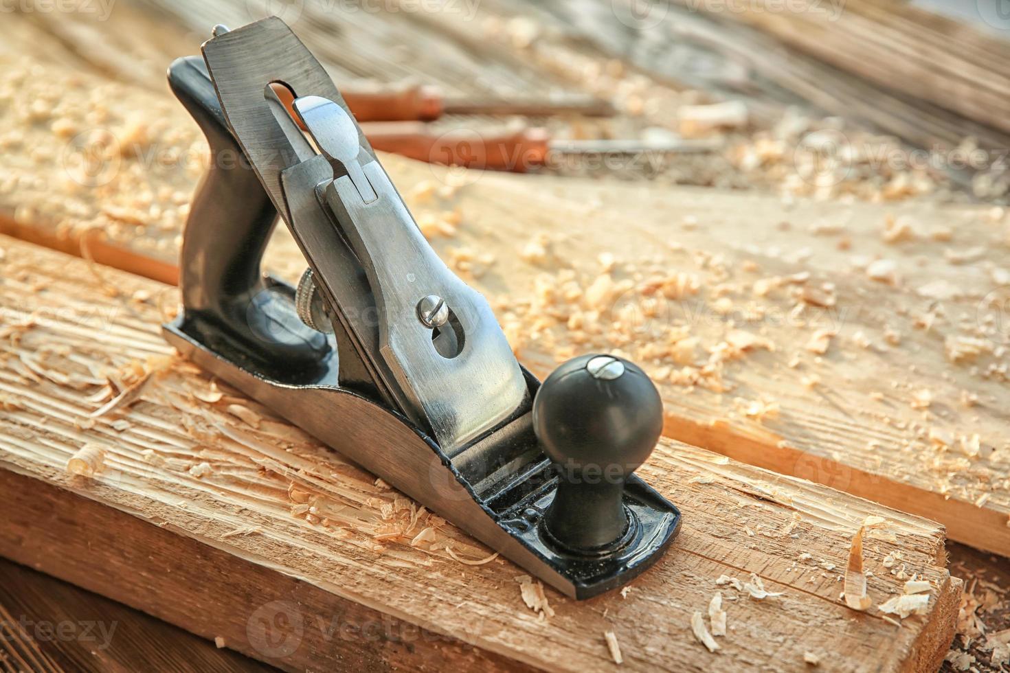 Smoothing plane, wooden boards and sawdust in carpenter's workshop photo