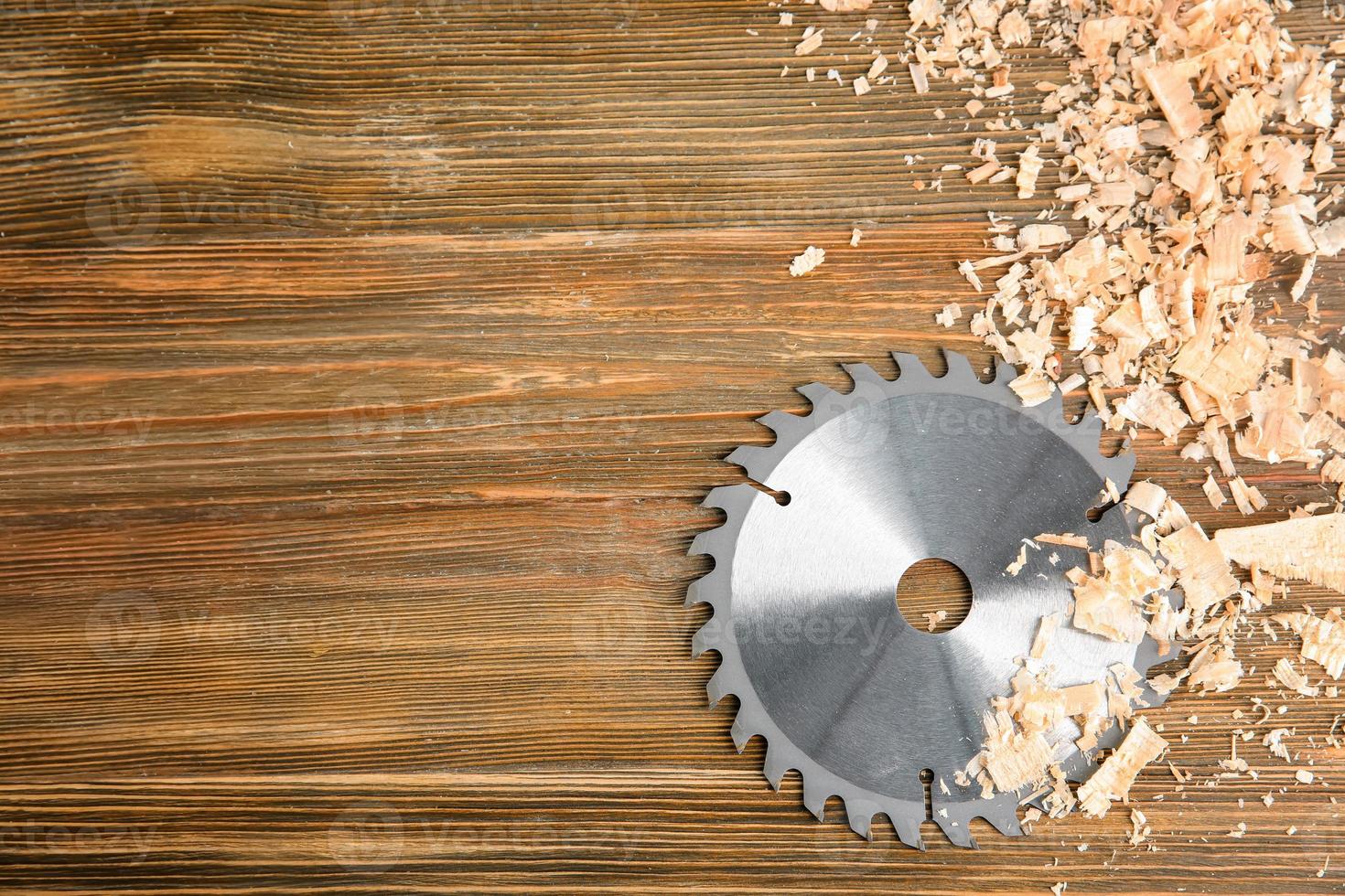 Circular saw disk on wooden background. Professional carpenter's equipment photo