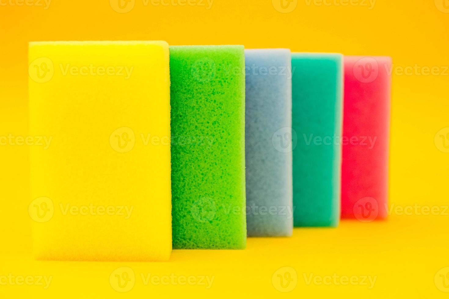 Esponja de goma espuma multicolor para limpiar y lavar platos sobre un fondo amarillo foto