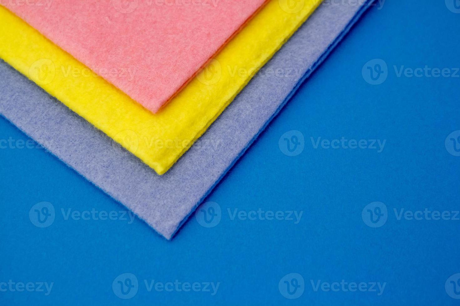 Multicolored cleaning rags on blue background photo