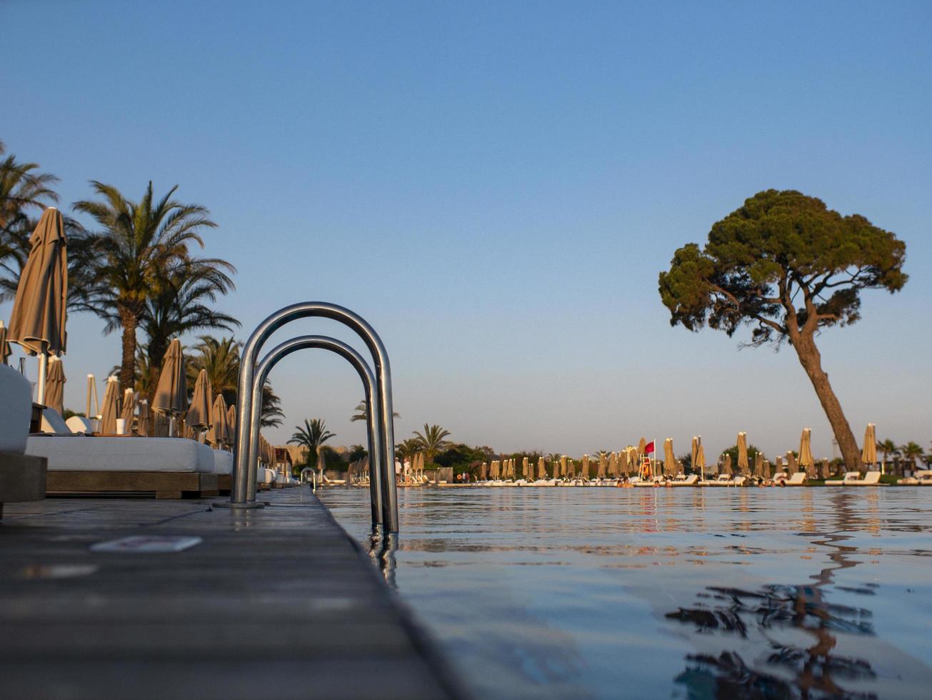 pasamanos en la piscina en el resort tropical. piscina de agua con reflejo. pasamanos de acero, natación, verano, viajes. entrada a piscina con pasamanos foto