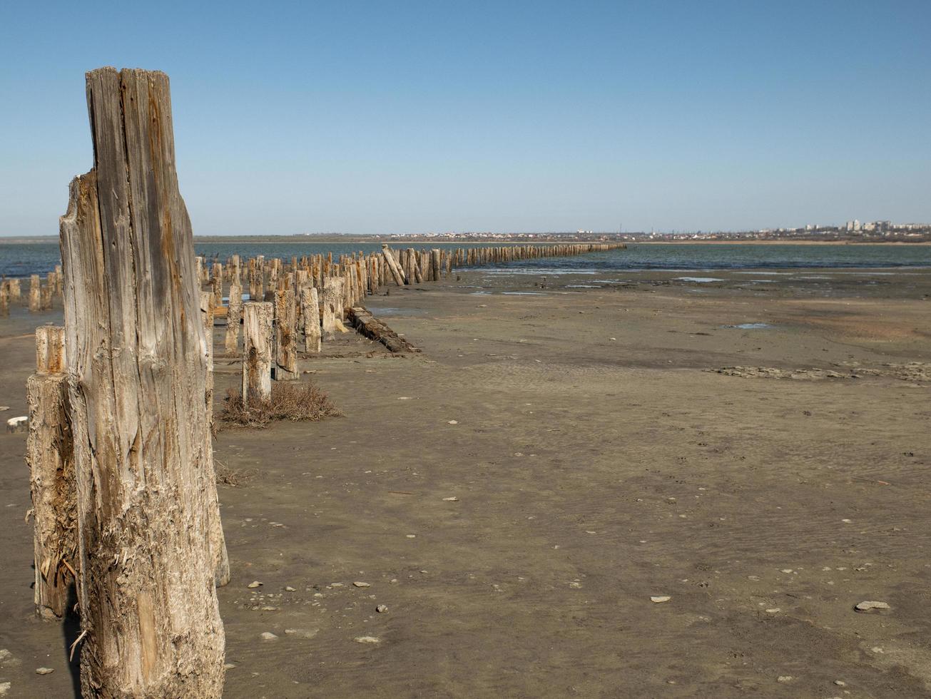 Bolardos de madera en la arena contra el estuario y el cielo azul. estuario kuyalnitsky foto
