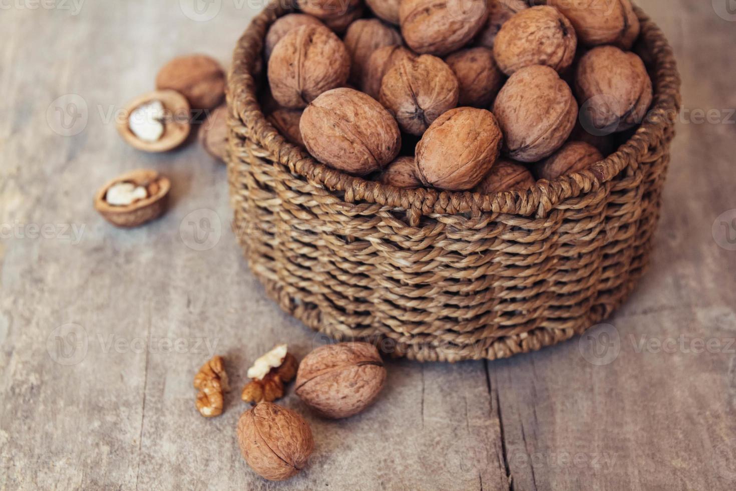 Nueces en una canasta de mimbre redonda sobre un fondo de madera foto