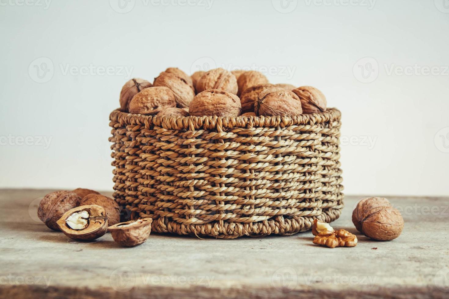 Walnuts in a round wicker basket on a wooden background photo