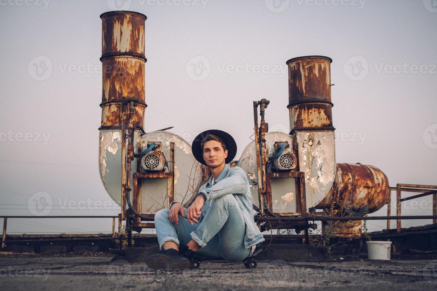 Man with skateboard on a background of rusty pipes photo