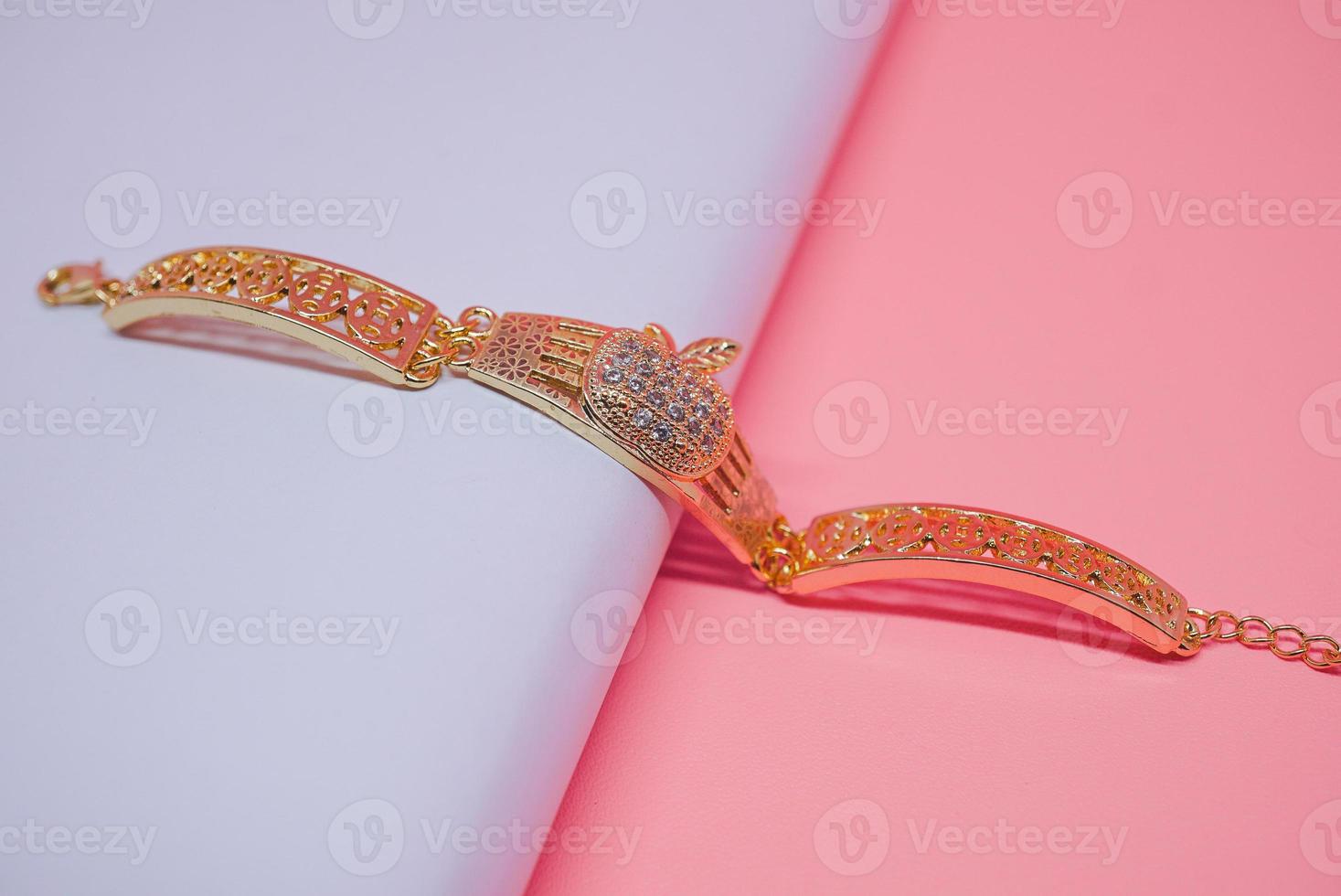 una foto de una pulsera de mujer con un motivo de manzana sobre un fondo rosa