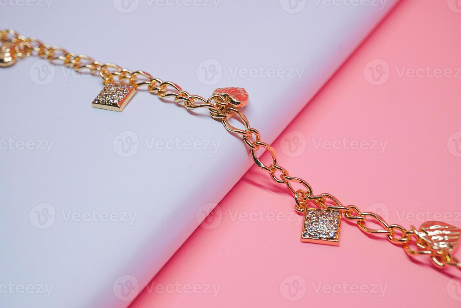foto de una pulsera de mujer con un patrón de cuadros y un motivo de amor sobre un fondo rosa