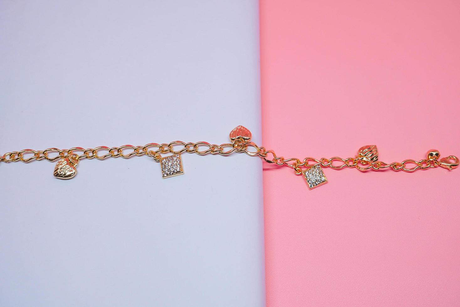 foto de una pulsera de mujer con un patrón de cuadros y un motivo de amor sobre un fondo rosa