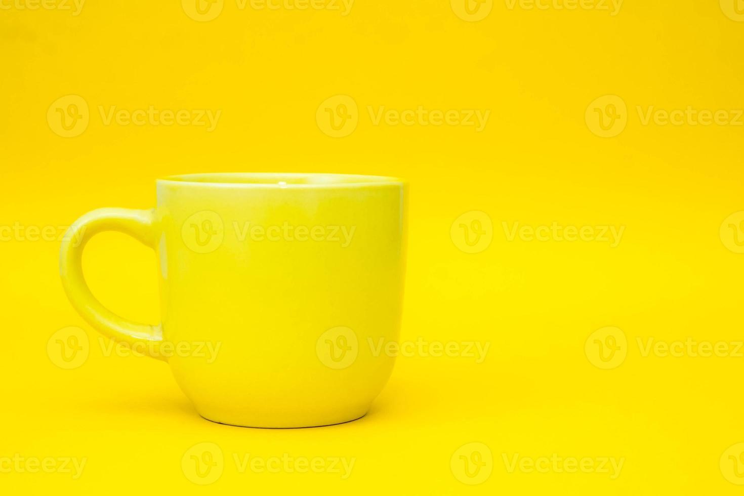 Yellow ceramic cup on yellow background photo