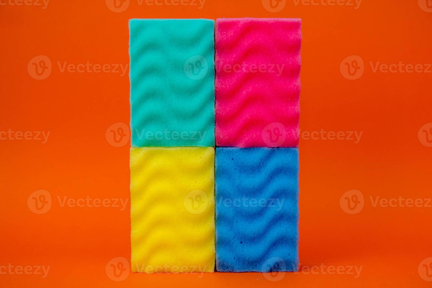Esponjas multicolores para limpiar sobre un fondo naranja foto