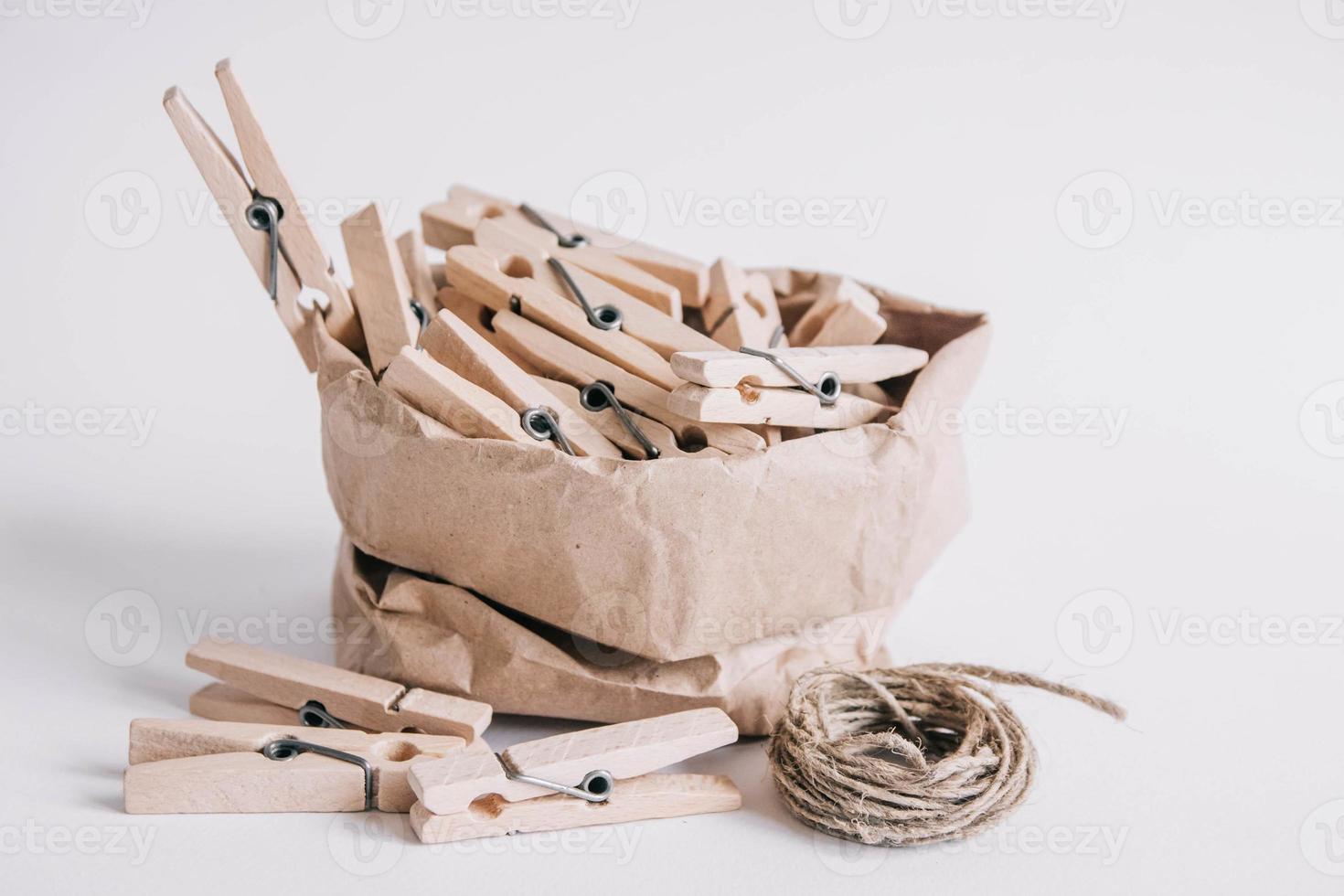 Pinzas para la ropa de madera en una bolsa de papel con una cuerda sobre fondo blanco. foto