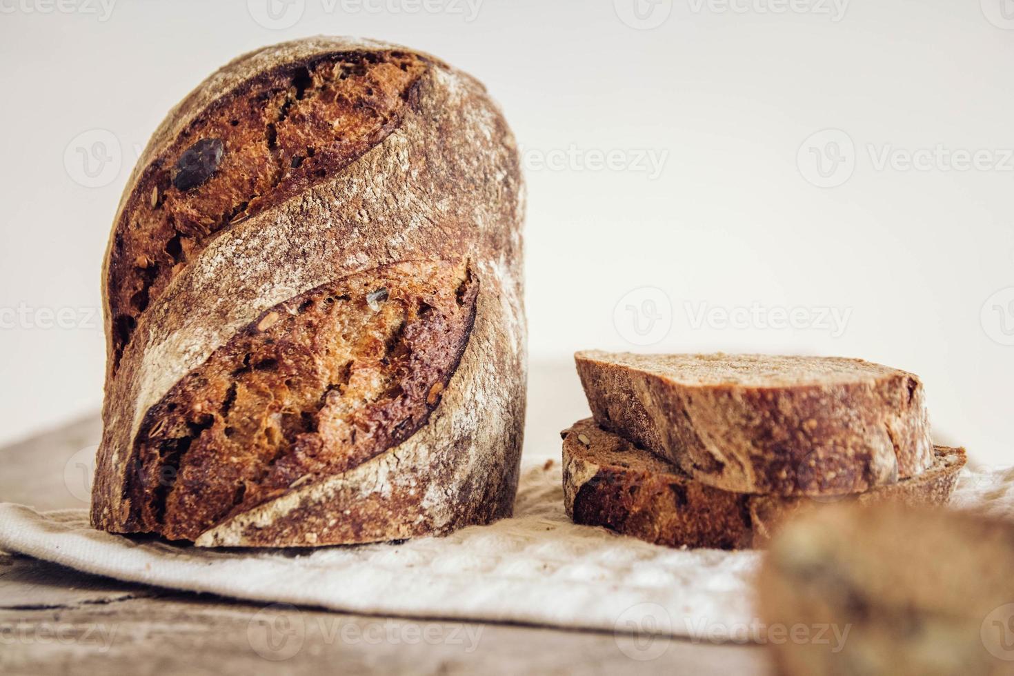 Brown fresh bread with seeds are cut into pieces on old wood background photo