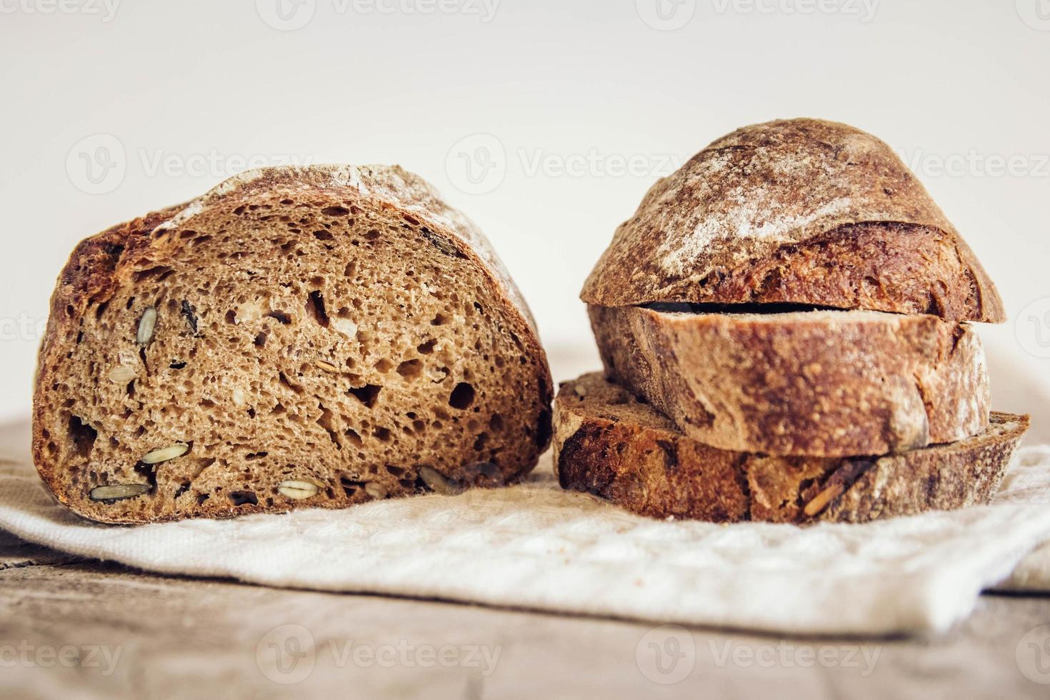 Pan fresco con semillas se cortan en trozos sobre fondo de madera vieja foto
